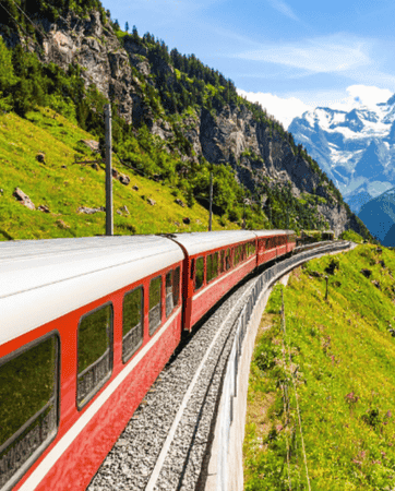 Red train driving through the Swiss Alps on a clear, sunny day